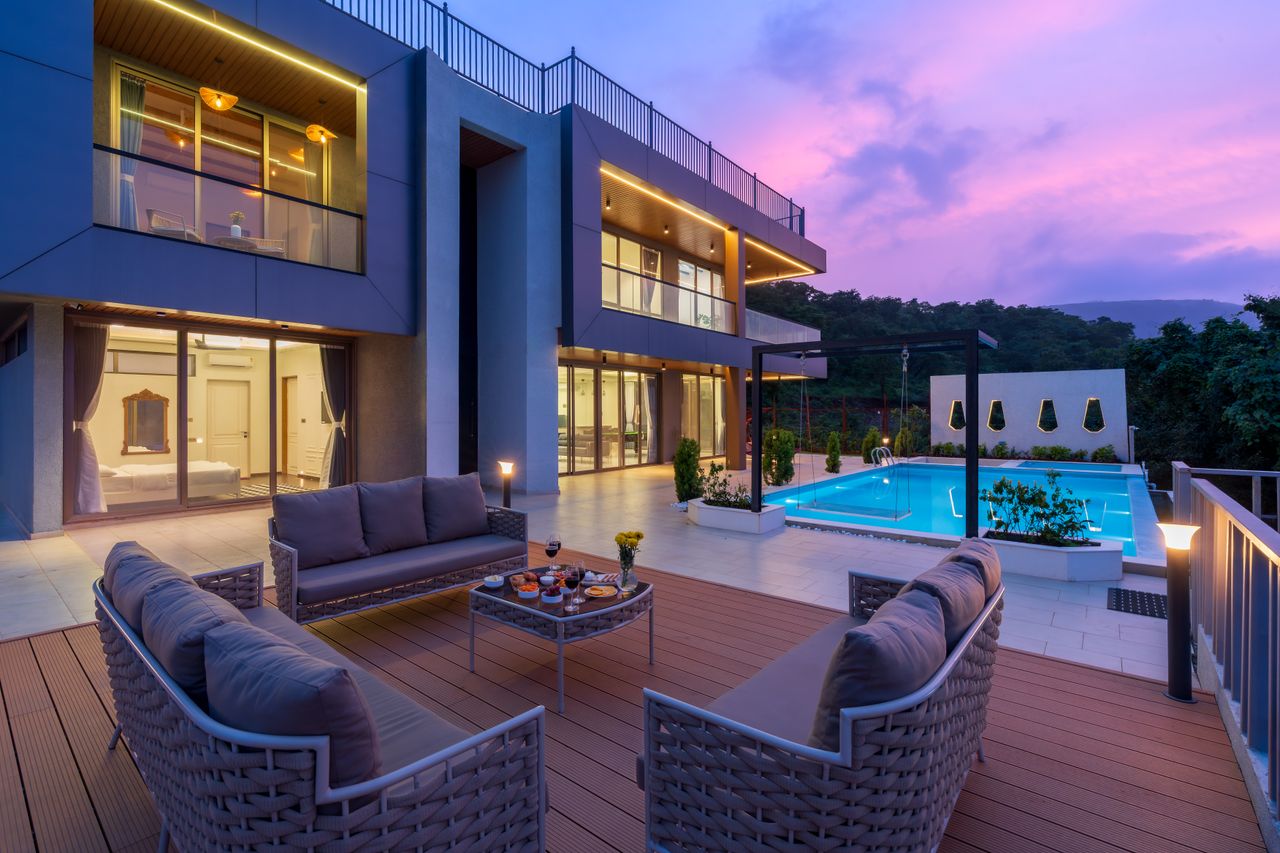 Stunning modern villa with outdoor seating and pool, captured at sunset.