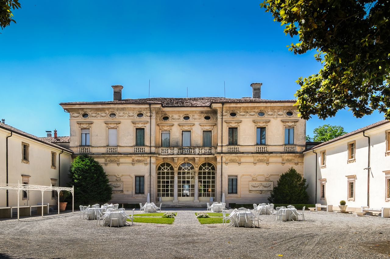 Beautiful courtyard of an Italian villa with outdoor seating under the summer sun.
